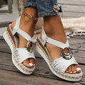 Close-up of women's silver wedge sandals with metallic ring and espadrille sole. - White