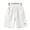 Detailed view of white corduroy men's shorts with drawstring and a decorative patch label. - White