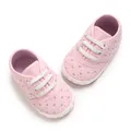Vista detallada de zapatos de bebé rosa con bordado de corazones y suela blanda para caminar. - Rosa