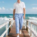 Dettaglio di uomo in polo bianca e pantaloni di lino azzurri su un molo sulla spiaggia - Taglia S / Top E Pantaloni / Top Bianco E Pantaloni Blu