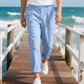 Men's light blue loose fit breathable linen trousers walking on a seaside pier. - Light Blue