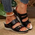 Close-up of black platform wedge sandals with intricate carved patterns and metallic buckles. - Black