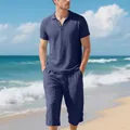 Close-up detail of men's navy blue linen polo and cropped pants set on a sunny beach - Navy Blue