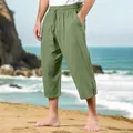 Detailed view of men's casual linen beach pants in sage green on a sunny shore - Green