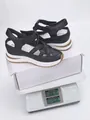Black wedge sandals with woven straps and velcro closure shown on weighing scale - 35 / Black with Brown Edge