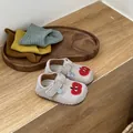 Primer plano de zapatos para bebé grises con bordado de manzana y suela blanda flexible - Beige