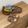 Primer plano de zapatos de bebé marrones con bordado de manzana y suela blanda para caminar. - Caqui
