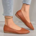 Detailed close-up of brown minimalist leather pointed toe flats worn on a model's feet. - Tan