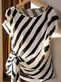 Close-up detail of stylish black and white diagonal striped blouse with elegant side-tie knot - Black