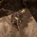 Primer plano de un broche de hoja dorada vintage con pedrería marquise de colores - Púrpura
