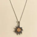 Detailed close-up of a vintage sun pendant necklace featuring a round amber moonstone. - Sun Style