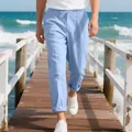 Close-up view of light blue men's loose linen beach pants on a scenic ocean wooden pier - Light Blue