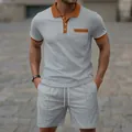 Close-up of men's grey waffle knit short sleeve polo and shorts set with brown trim detail. - Gray