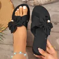 Detailed view of black flat slippers with elegant bow and pearl accents for summer beach - 36 / Black
