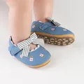 Dettaglio del motivo a fiori ricamati e fiocco a righe su scarpe in denim per neonata - Celeste