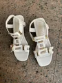 Detailed view of white Roman style flat sandals with golden decorative hardware. - 38 / White