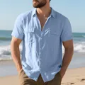 Detail of men's light blue short sleeve linen shirt with chest pockets on beach. - S / Tops / Light Blue