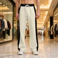 Close-up of men's heavy terry sweatpants with black side stripes in mall setting - S / Bottoms / Apricot/Black
