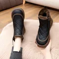 Detalle de botas de nieve acolchadas negras con suelas marrones y forro de pelo sintético - Negro