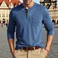 Close-up of men's casual blue long-sleeve Henley shirt in a European outdoor setting. - Denim Blue