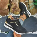 Detailed view of black wedge sneakers with gold accents and a white platform sole. - 36 / Black