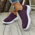 Detail view of purple breathable fly-knit slip-on sneakers on a wooden deck. - Deep purple