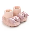 Close-up detail of soft pink fleece-lined baby booties with a decorative satin bow accent. - Pink