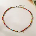 Detail view of a colorful turquoise seed bead necklace featuring heart and gold 'L' letter charms - Letter L