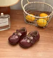 Klassische weinrote T-Strap-Lederschuhe für Kleinkinder auf rustikalem Holztisch präsentiert - Größe 36 Innenlänge 22 / Burgunderrot