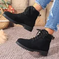 Detail view of black British style lace-up ankle boots worn with denim jeans. - Black