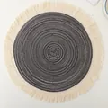 Top-down view of a circular woven cotton placemat featuring decorative cream fringes - 12-Piece Set / Dark Gray