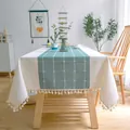 Detail view of sage green and beige grid table runner with elegant tassel edges - 100*140cm / Green