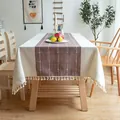 Detail view of embroidered grid pattern and tassels on cream and brown tablecloth. - 100*140cm / Fuschia