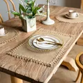 Sets de table rustiques en toile de jute avec franges sur une table à manger en bois - Jute Cross Knot Lace