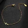 Detail eines goldenen Edelstahl-Kreuzarmbands mit grauen Emailleperlen auf Schwarz - Gold Reinheit / Grau