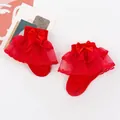 Detailed view of red baby socks with double tulle ruffles and satin bow accents - One Size (0-1 Year Old) / Red