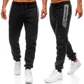 Close-up of men's black fitness joggers featuring grey side panels and a zipper pocket - S / Bottoms / Black