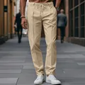 Detailed view of men's khaki drawstring trousers in a stylish urban street setting. - S / Bottoms / Khaki