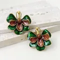 Close-up of vintage enamel flower earrings with green and red petals and gold trim. - Green