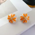 Nahaufnahme von Vintage-Emaille-Ohrsteckern mit orangefarbenem und weißem Emaille-Detail - Rund Weiß