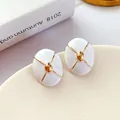 Close-up of vintage white enamel earrings with gold cross pattern and silver needle - White