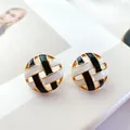 Close-up of vintage round hollow-out enamel stud earrings with black and white woven pattern. - Round Black White