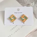 Macro detail of vintage French enamel square stud earrings with pearl trim and gold finish. - Square Post