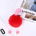 Close-up of a pink flamingo pompom keychain with a red faux fur ball and gold clasp - Red