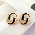 Close-up detail of vintage round hollow enamel stud earrings in black white and gold - Square Black And White