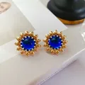 Vue détaillée de boucles d'oreilles tournesol vintage dorées avec une gemme bleue - Tournesol Bleu