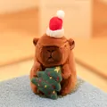 Adorable Christmas themed Capybara plush doll wearing a red Santa hat holding a tree - Holding Christmas Tree