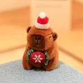 Cute Capybara plush toy wearing a Christmas hat and holding a red snowflake ornament. - Holding Christmas Candy