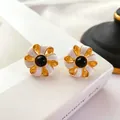 Vue détaillée de boucles d'oreilles fleurs en émail baroque vintage avec centres noirs - Combinaison Blanc et Noir
