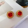 Gros plan de boucles d'oreilles vintage avec gemme rouge et bordure dorée - Cercle Rouge